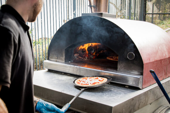 a pizza is taken out of a wood fired oven