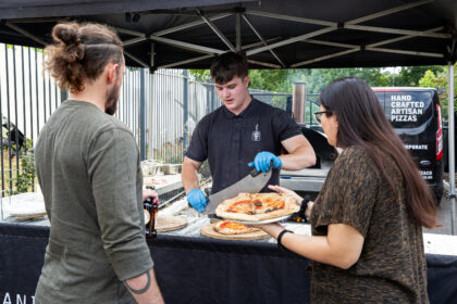 a man serves pizza to two people